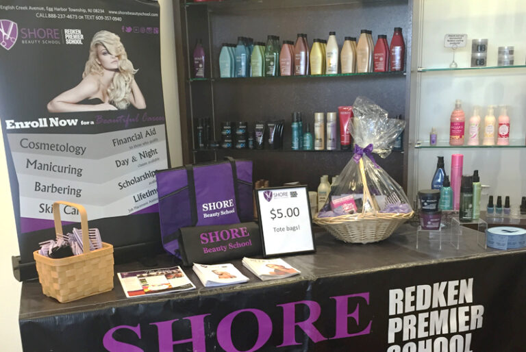 Shore Beauty School booth with products, banner, tote bags, and brochures at promotional event.