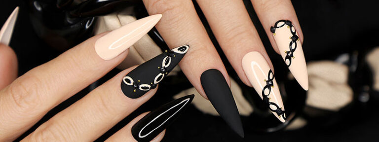 Stiletto nails with chic black and beige manicure, featuring intricate designs and glossy finish.
